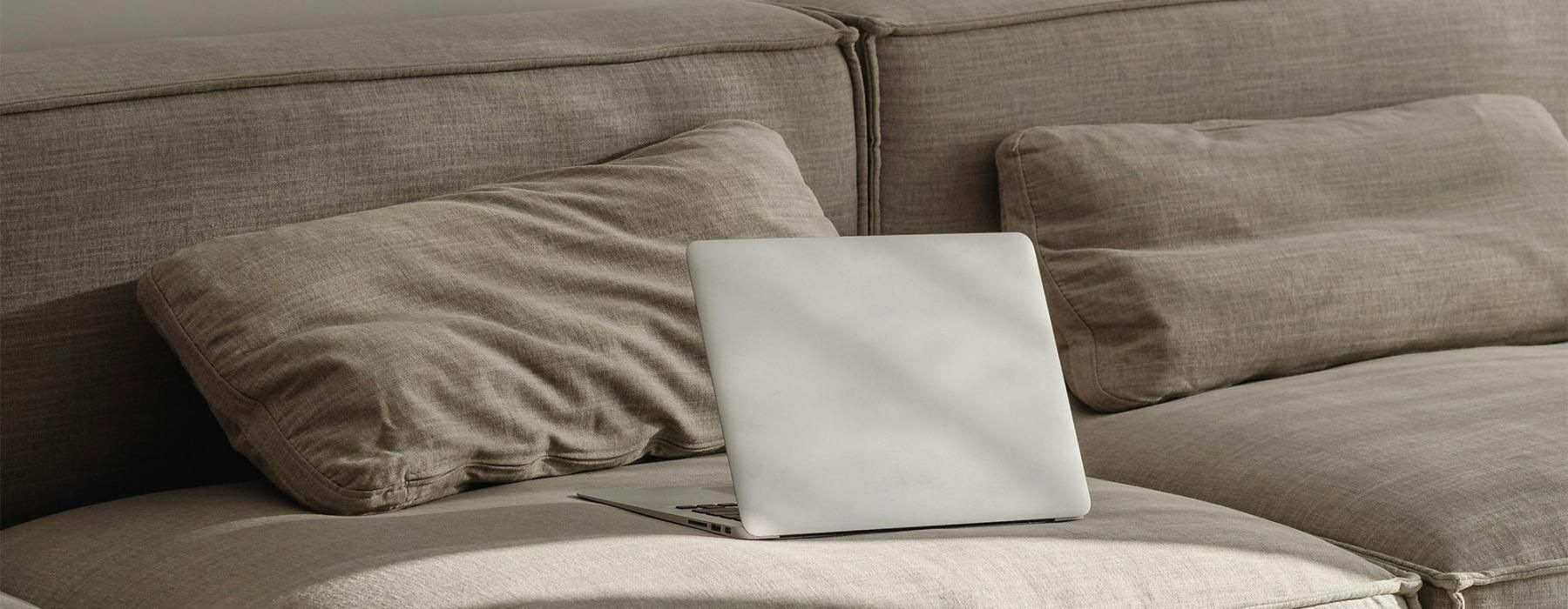 a couch with pillows and a laptop